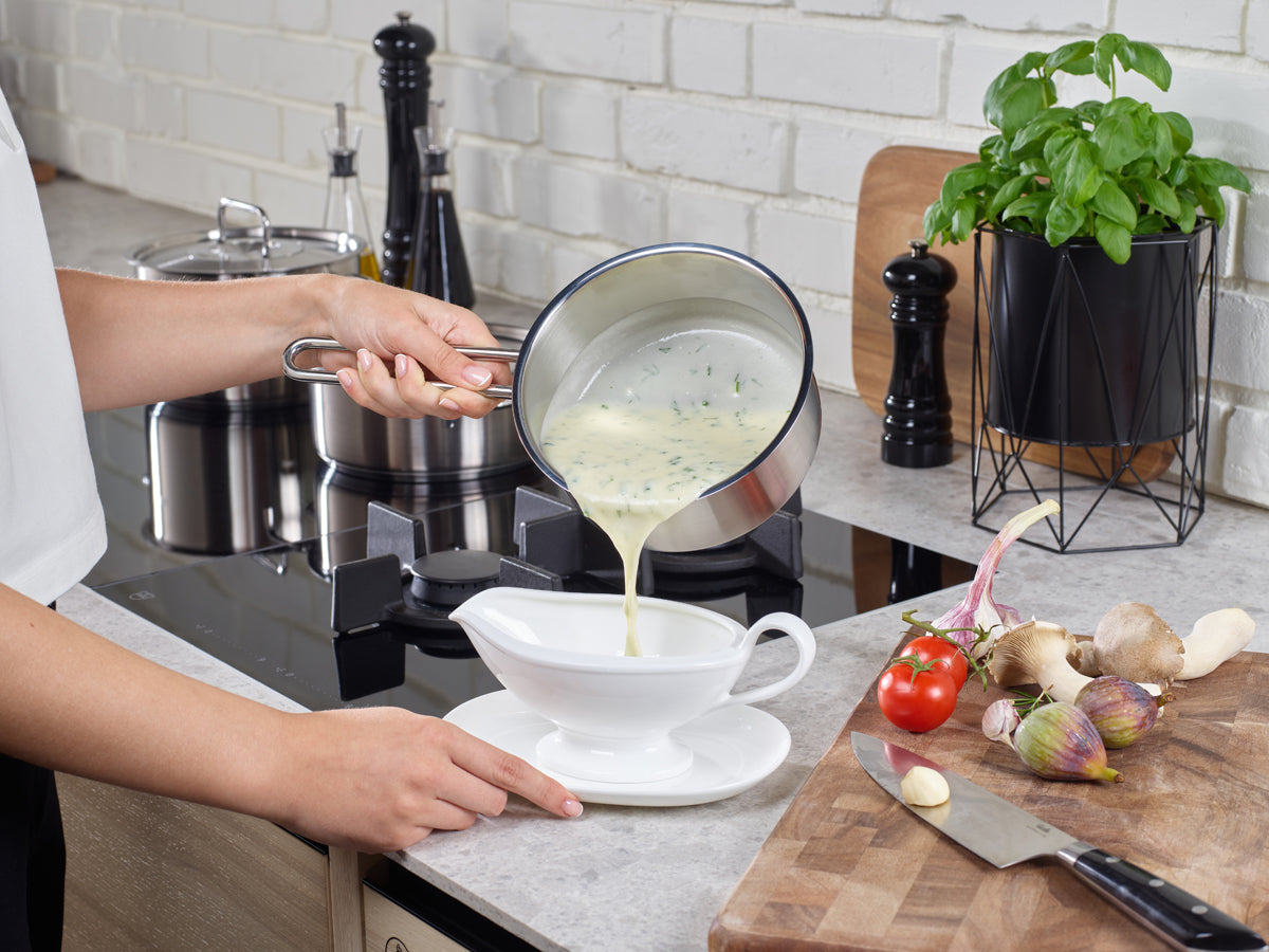 Die cremige Kräutersuppe wird aus einem Fissler Pure Collection®-Topf - zeitlose deutsche Qualität - in einer Schale serviert, umgeben von frischem Gemüse.