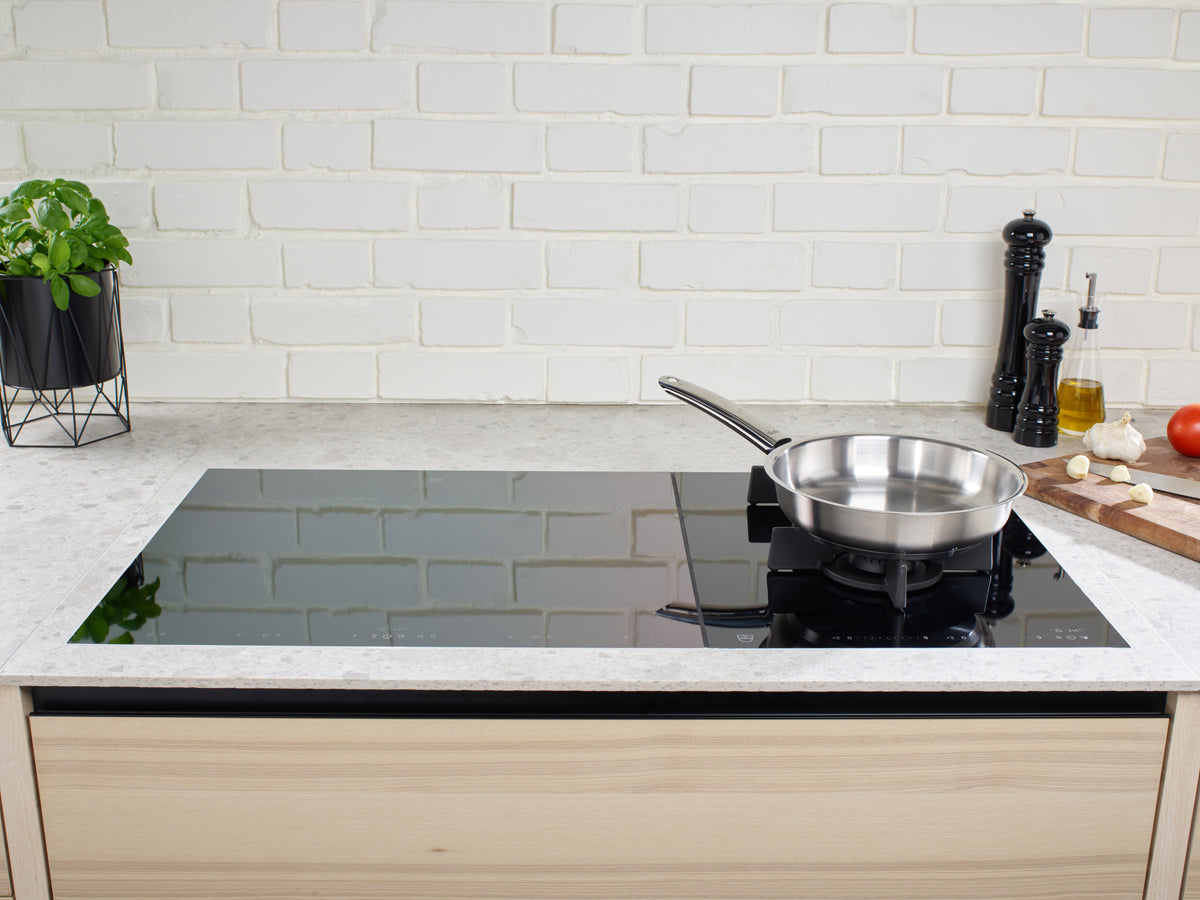 A modern kitchen with a Fissler Pure Collection Frying Pan on an induction hob, fresh ingredients, and classic German quality design.