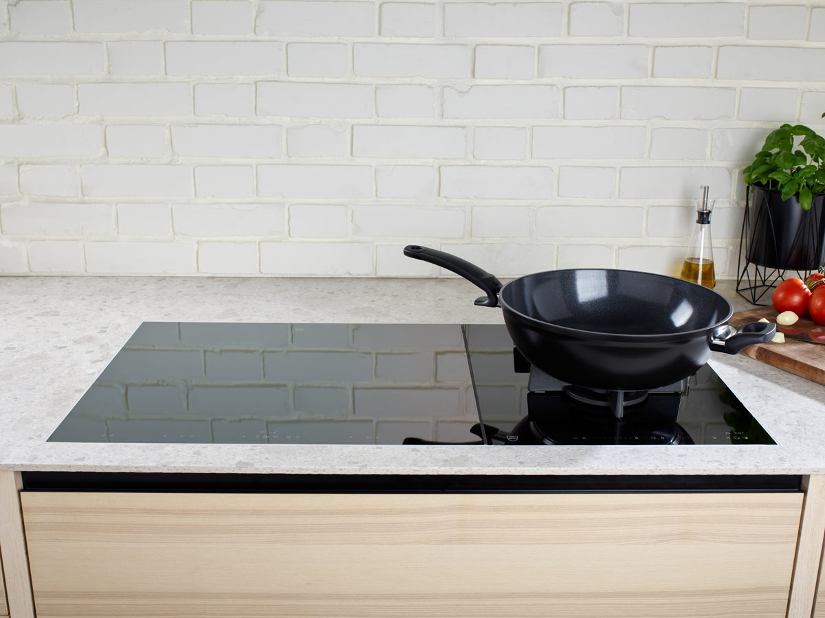 A modern kitchen is enhanced by the Fissler Ceratal® PTFE-free wok in orbit black with fresh ingredients and German precision design.