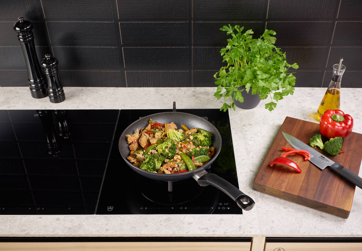 Fissler Adamant® Classic Pfannenset im Einsatz auf dem Herd mit Rührbraten, frischen Zutaten - Präzision und Haltbarkeit "Made in Germany".