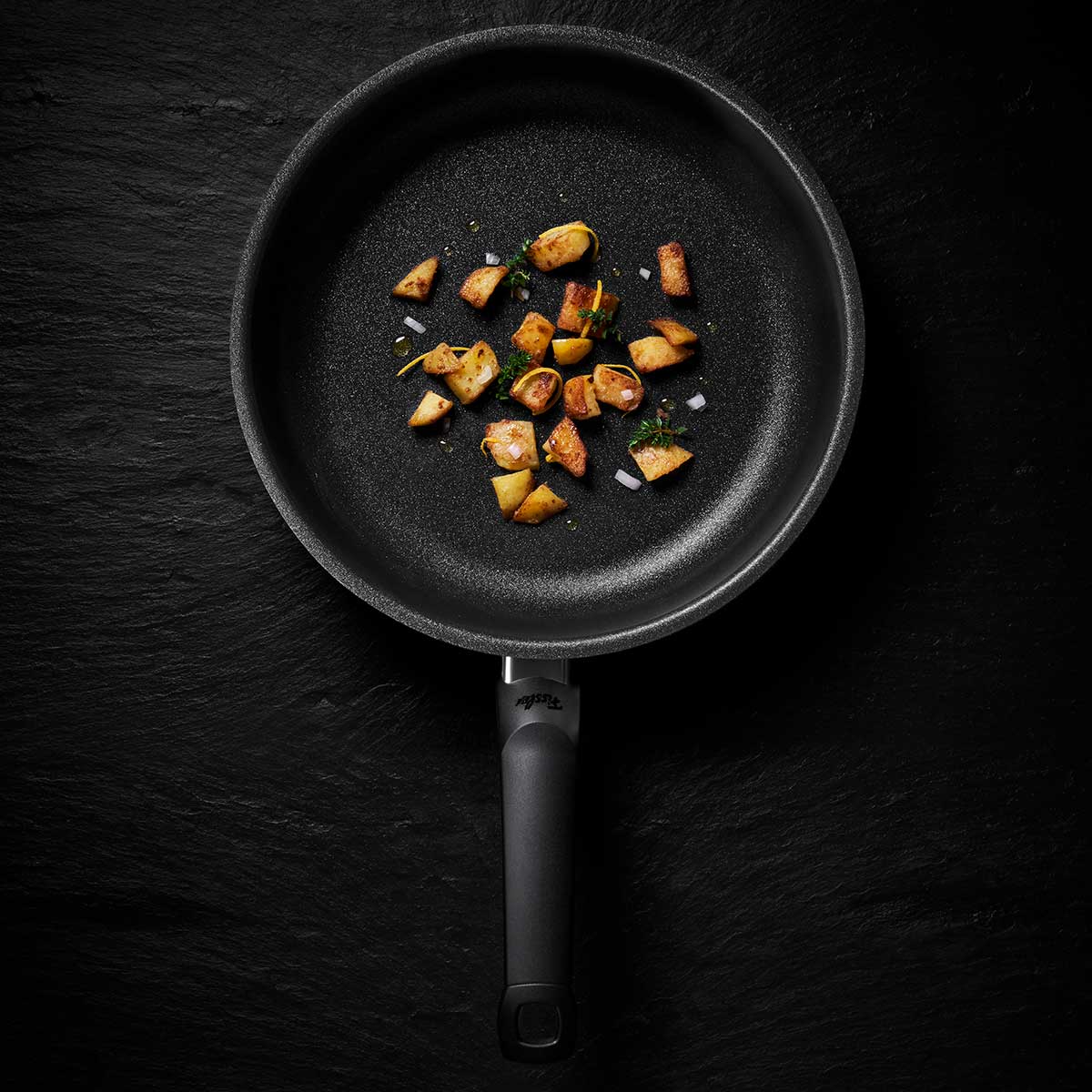 Fissler Adamant® Premium Frying Pan with fried potatoes, featuring German non-stick quality and timeless, durable design.
