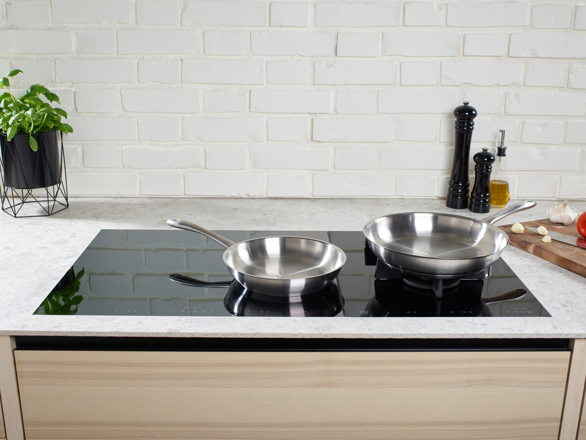 Two Fissler Catania pans on an elegant induction hob in a modern kitchen - timeless German design, made for everyday use.
