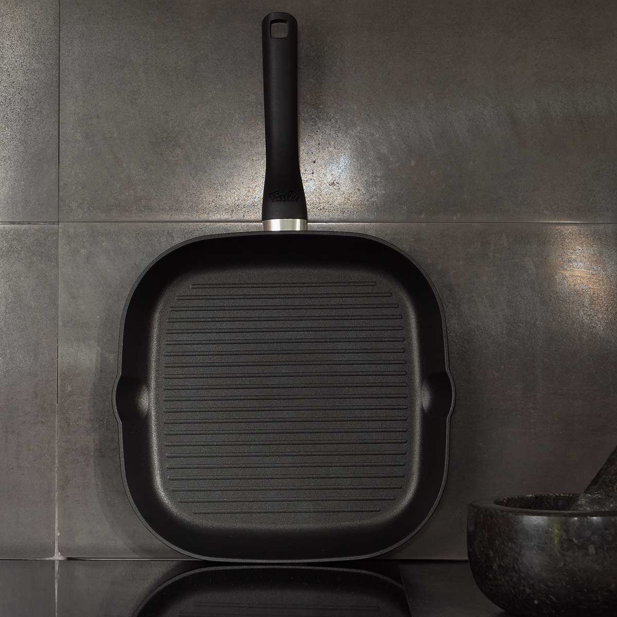 The Fissler Cenit® Grill Pan Induction 28 cm stands upright and impresses with German design, modern ridges, and a long handle.
