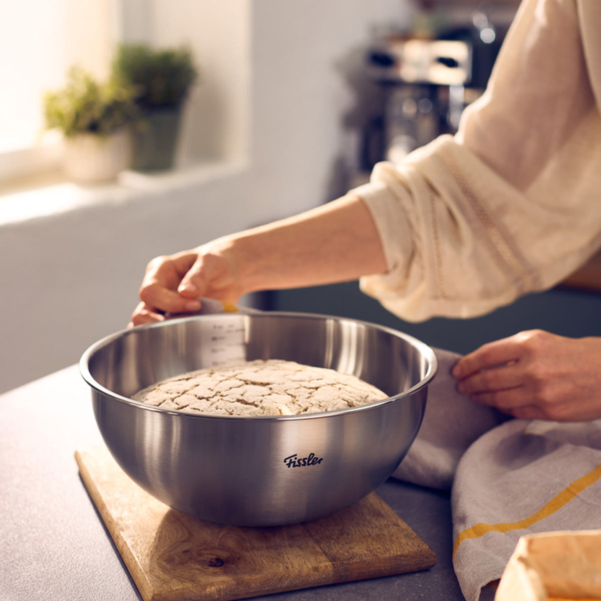 A person presents proofed dough in a 24cm Fissler Essential® bowl, embodying German precision and timeless kitchen design.