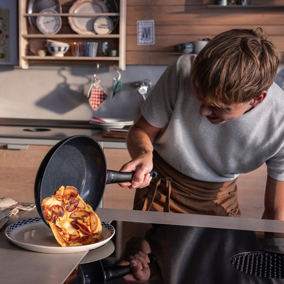 In a modern kitchen, Fissler Essential® pans (24 cm & 28 cm) help you slide a filled omelet onto a plate - quality made in Germany.