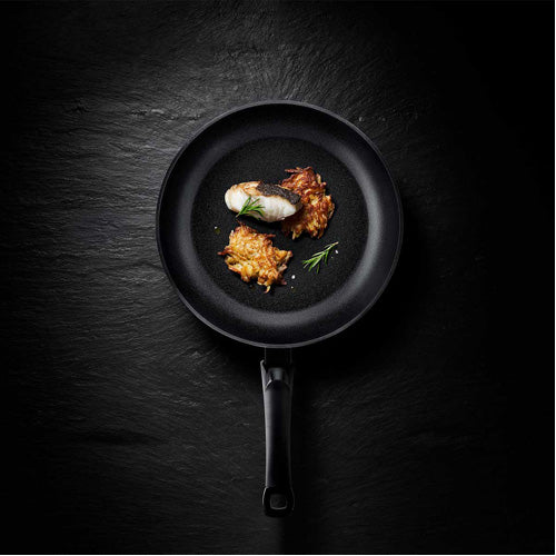 Fissler Levital®+ Classic Pan with cooked fish, potato pancakes, and rosemary - precise German design, modern and functional.
