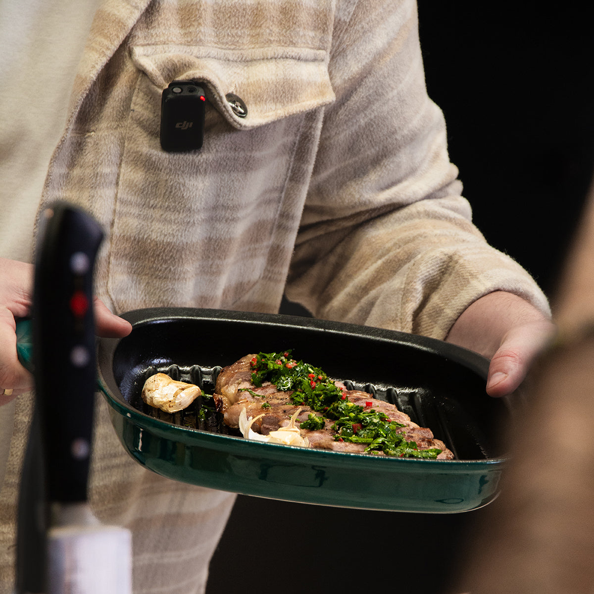 A person holds a Fissler Original-Profi Collection® cast iron grill pan with a steak; modern German design, knife in the foreground.