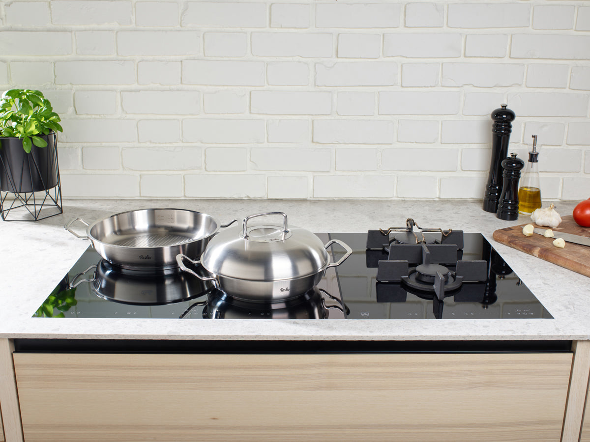Fissler Original-Profi Collection® high-domed lids and stainless steel pans on a sleek stovetop - timeless German design and quality.