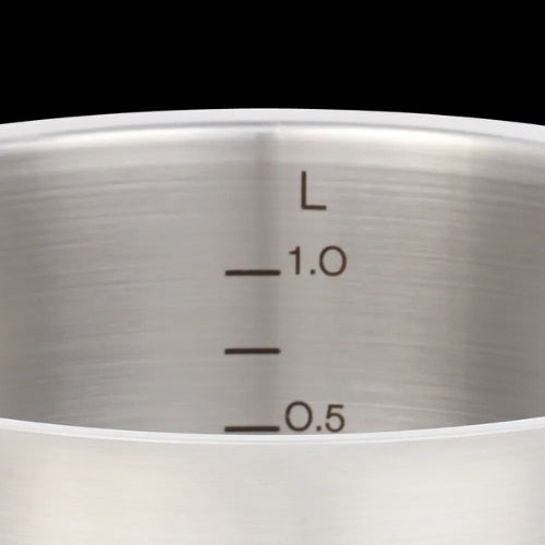 Nahaufnahme eines Fissler-Edelstahltopfs mit präzisen schwarzen 0,5- und 1,0-L-Markierungen, die deutsche Technik auf schwarzem Hintergrund zeigen.