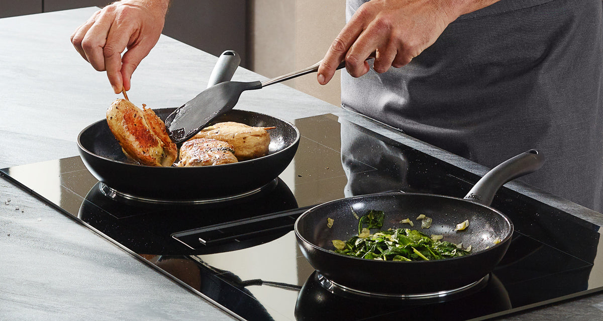 The chicken breast is seared in a Fissler Essential® Frying Pan with a stainless steel spatula, while the vegetables are sautéed in another precision pan "Made in Germany".
