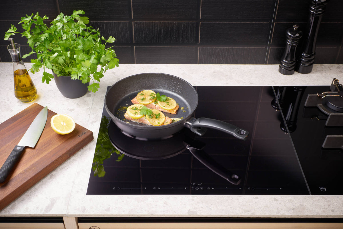Fissler Adamant® Comfort Frying Pan Set (24 cm & 28 cm) on an induction hob, fresh ingredients within reach; German precision since 1845.