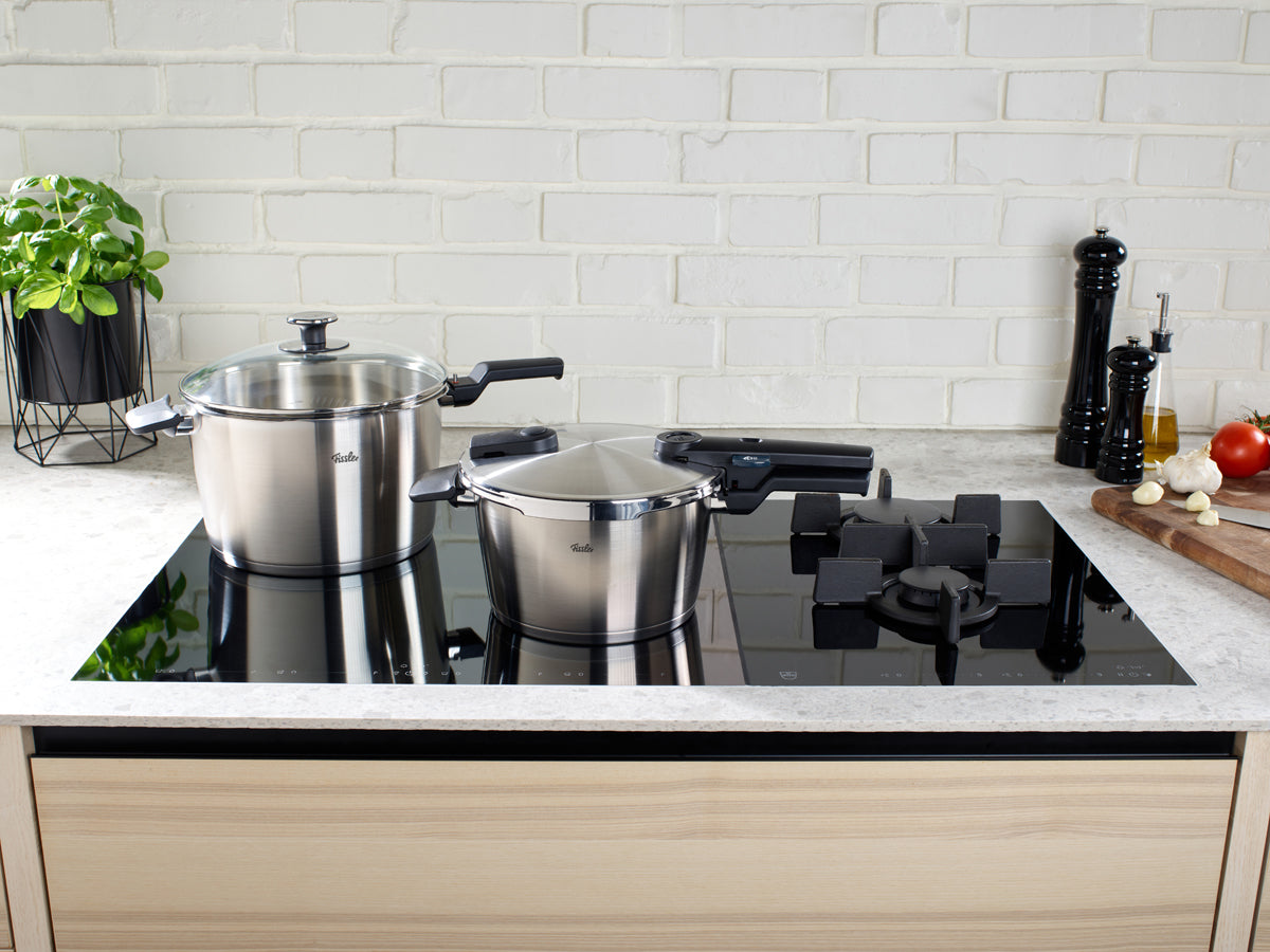 Fissler Vitaquick® Premium 2-pc. Pressure Cooker Set on the stovetop, with fresh herbs and kitchen appliances in a timeless design.