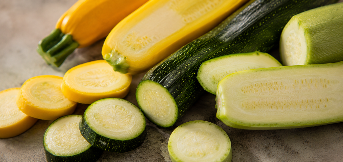 Gelbe und grüne Zucchini, sowohl ganz als auch in Scheiben geschnitten, sind auf einem hellen Untergrund angeordnet – perfekt in Szene gesetzt, um ihre leuchtenden Farben und ihre frische Konsistenz zur Geltung zu bringen. Eine ideale Präsentation der Zutaten, bereit zum präzisen Schneiden oder Garen in hochwertigem Fissler-Edelstahlgeschirr, bei dem innovatives Design auf zeitlose deutsche Handwerkskunst trifft.