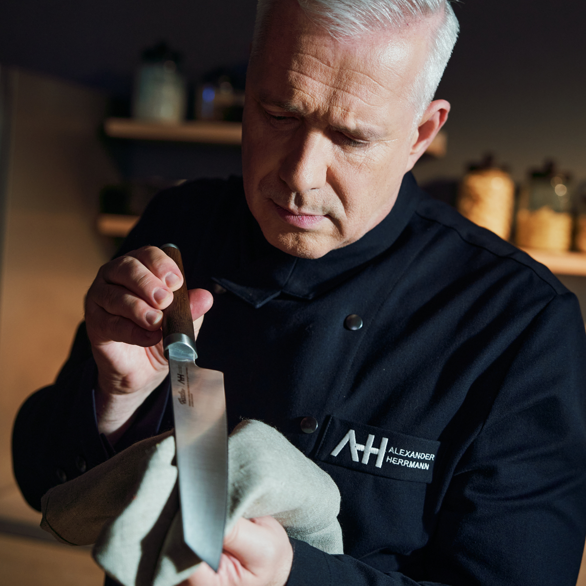 Chefkoch Alexander Herrmann poliert ein hochwertiges Fissler-Küchenmesser, das deutsche Präzision und Qualität in einem modernen Küchenambiente demonstriert.