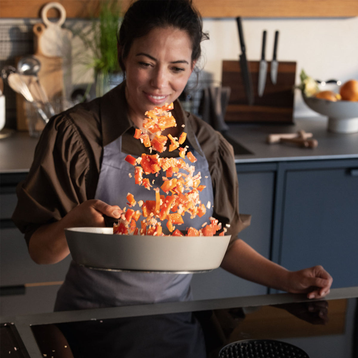 alt
A woman smiles while cooking with a Fissler frying pan in a modern kitchen, surrounded by high-quality cookware and fresh ingredients.