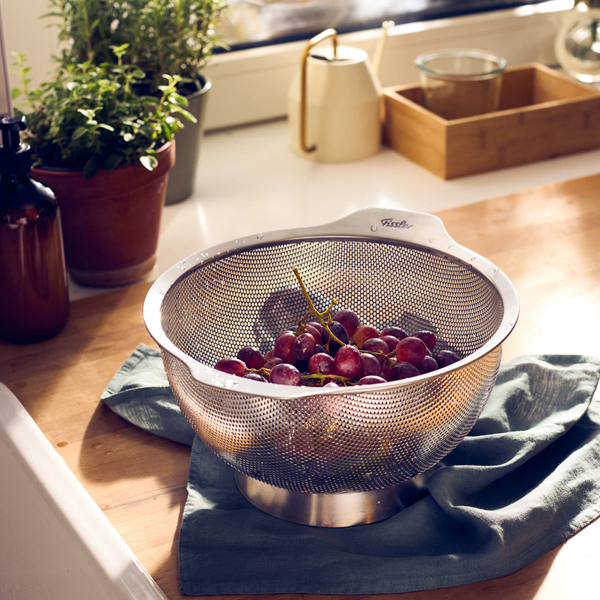 Das in Deutschland gefertigte Fissler Essential® Sieb 24cm hält rote Weintrauben auf der Küchentheke und zeigt zeitlose Fissler-Qualität.