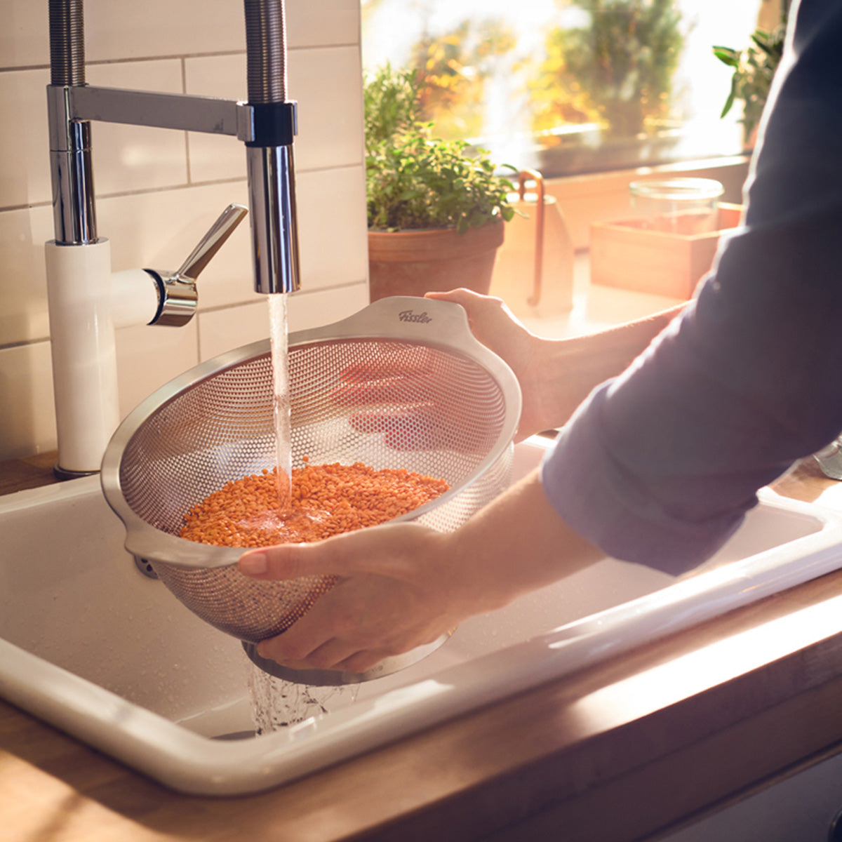 Spülen von roten Linsen in einem Fissler Essential® 24cm Edelstahlsieb, das in Deutschland für dauerhafte Präzision und Qualität entwickelt wurde.