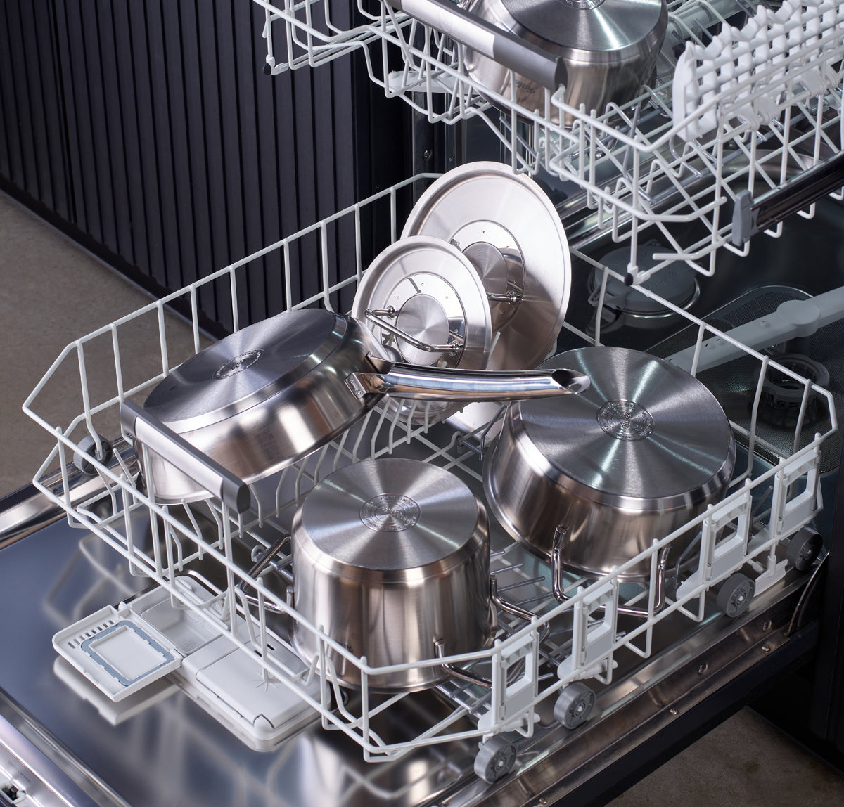 Offene Geschirrspülmaschine mit Töpfen, Pfannen und Deckeln aus der Fissler Pure Collection aus rostfreiem Stahl auf Einlegeböden - ein Zeichen für Qualität aus deutscher Produktion.