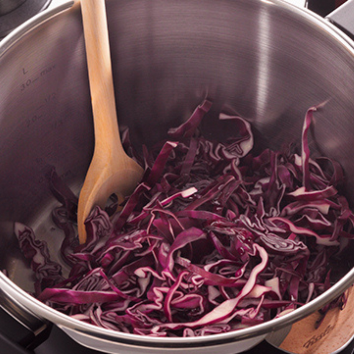 Frisch zerkleinerter Rotkohl im hochwertigen Fissler-Edelstahltopf mit Holzlöffel, der von deutscher Ingenieurskunst zeugt.