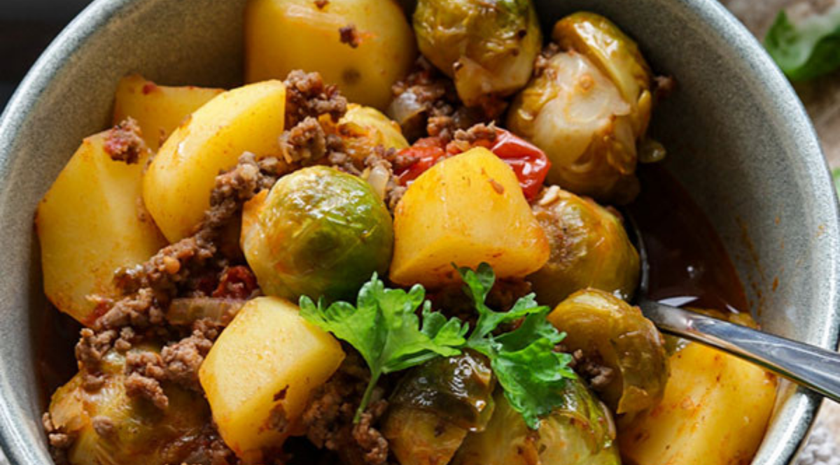 Herzhafter Eintopf mit Kartoffeln, Rosenkohl, Rindfleisch und Tomaten, serviert in einer Schüssel - perfekt zubereitet im Fissler Kochgeschirr.