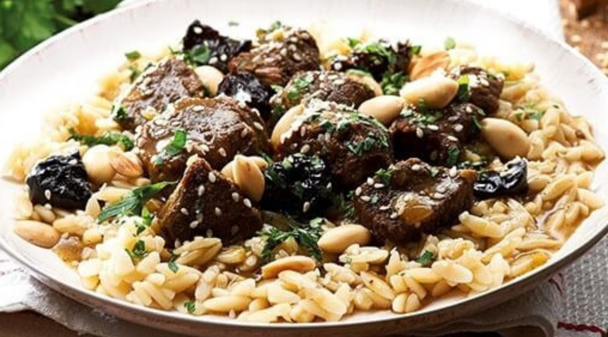 Orzo-Pasta mit geschmortem Rindfleisch, Mandeln, Pflaumen, Sesam und Petersilie - kunstvoll angerichtet mit der Präzision von Fissler-Kochgeschirr.