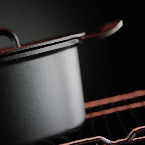 Eine Nahaufnahme eines Fissler Gusseisentopfs mit Deckel auf einem Backofengestell, der deutsche Präzision, Langlebigkeit und zeitloses Design demonstriert.