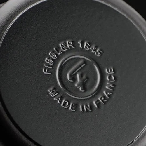 Nahaufnahme eines schwarzen Kochgeschirrs mit der Prägung FISSLER 1845 MADE IN GERMANY und dem Logo, das für deutsche Handwerkskunst steht.